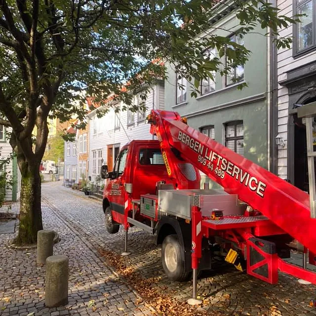 Rød tak i bygata med store trær